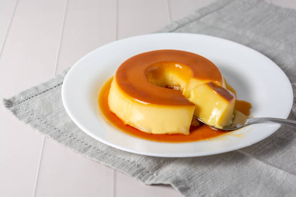 Spoon rests on a plate with a creamy dessert.
