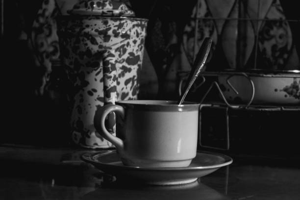 Minimalist photograph of a white ceramic cup filled with black coffee placed on a white and black background.