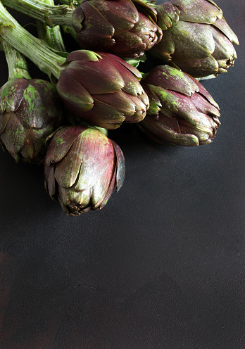 A group of fresh organic artichokes on isolated on black background. Healthy and vegetarian food. Overhead view.