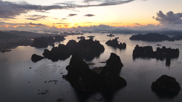 Aerial Drone Sunrise Scene of A Traditional Floating Village by Karst Formations with Rocky Mountain in Halong Bay near Halong City in Vietnam a World Heritage Site.