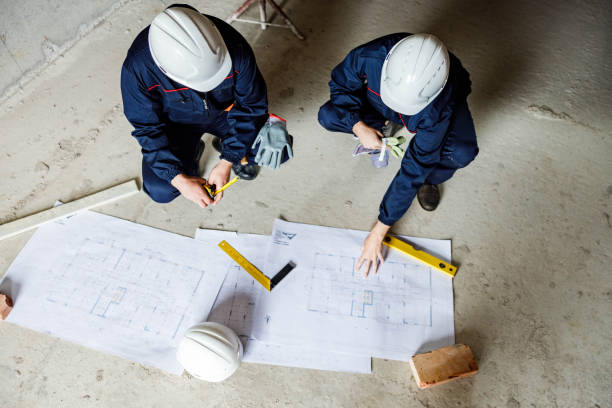 istock Above view of manual workers analyzing blueprints at renovation site. 2044808247