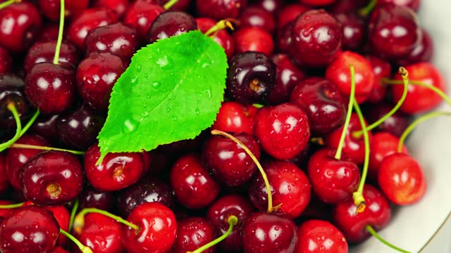 Fresh Ripe Cherries With Water Droplets Rotating In A White Bowl