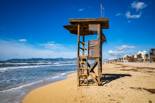 A wooden beach lifeguard hut on sandy shore.
