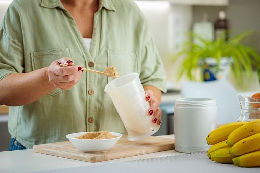 Close up of a woman mixing nutritional supplement powder in her kitchen. High resolution 42Mp indoors digital capture taken with SONY A7rII and Zeiss Batis 40mm F2.0 CF lens