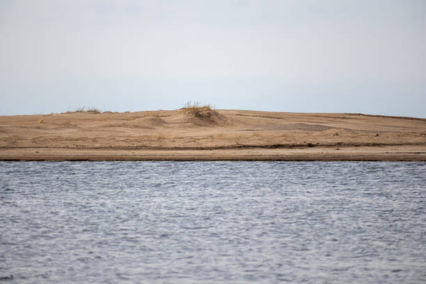 Horizontal lines with blue water brown sand and gray sky edge