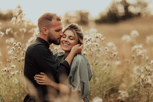 Couple, hug and kiss for love, care or compassion in happy relationship, bonding or free time on mockup. Woman smiling with man kissing cheek and hugging in romantic quality bonding together outside