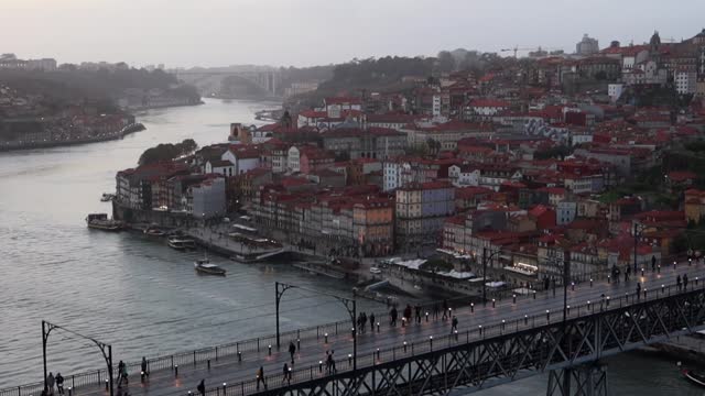 People walking across Dom Luis I Bridge between Porto and Gaia at sunset