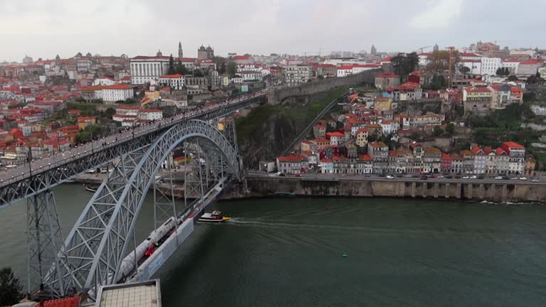 Rabelo boat navigates under Dom Luis I Bridge while people cross over it. Static