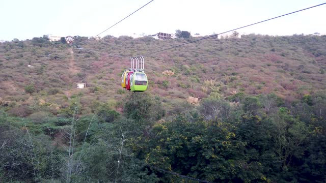 An Eye catching view of Cable cars in vibrant colors on a rope away descending through a hilly terrain in Udaipur city in Rajasthan, India.