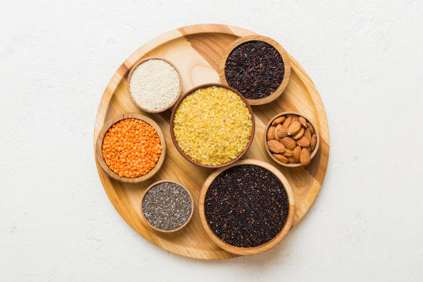Various superfoods in smal bowl on colored background. Superfood as rice, chia, quinoa, lentils, nuts, sesame seeds, almonds. top view