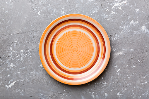 Top view of empty orange plate on cement background. Empty space for your design.