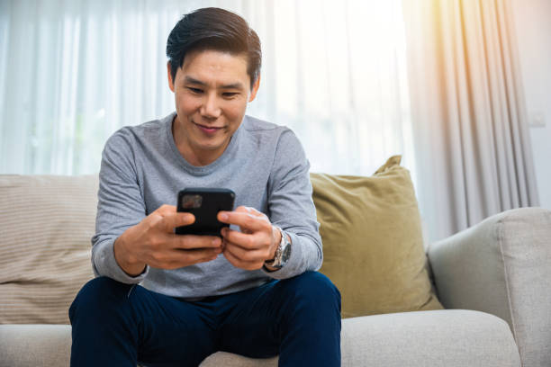 istock middle aged man relaxing sitting on sofa using smart mobile phone at home 2045080975