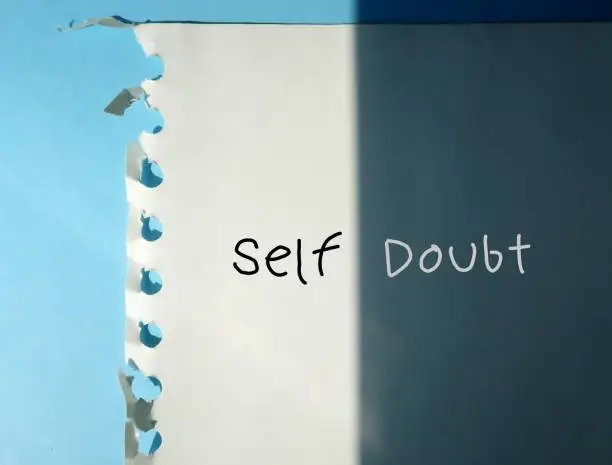 Note on shadow background with handwritten text SELF-DOUBT, overcoming doubting yourself, lack of confidence mindset that holds back from success