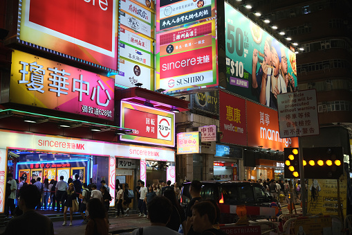 Crowd of people walking on the neon lighten streets in Mong Kok district, Kowloon, Hong Kong