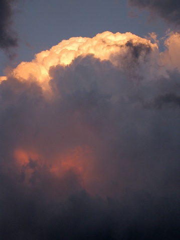 Cumulonimbus clouds bathe in the setting sun, creating a dramatic landscape.