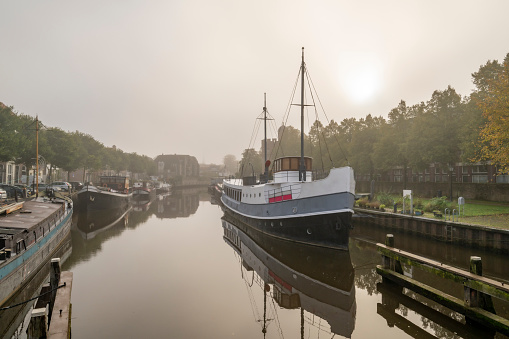 View on the Thorbeckegracht in Zwolle, Overijssel The Netherlands, during a beautiful misty autumn morning day classic sailing freight ships in the canal during a foggy morning.