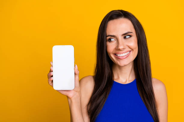 istock Photo of dreamy shiny lady dressed blue top looking apple iphone samsung modern gadget empty space isolated yellow color background 2045131259