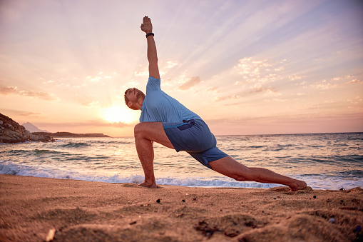 Active man exercising on the beach at sunset.