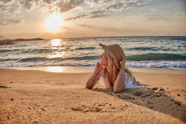 Beautiful woman lying down on the beach at sunset.