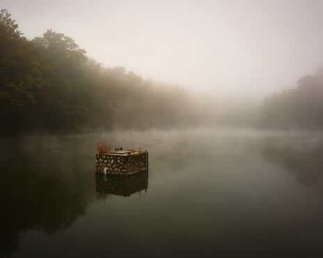 A small island drifts on mist-covered lake