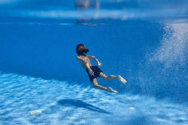 istock Unrecognizable barefoot boy swimming in blue pool 2045200302