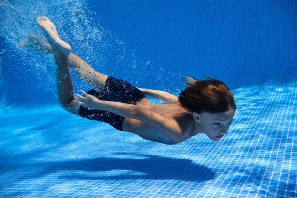 istock Kid in swimsuit diving into pool 2045200340