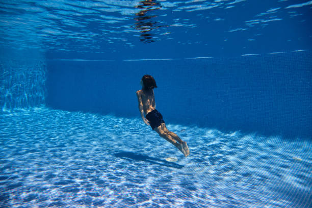istock Boy swimming towards surface of tiled pool 2045200881