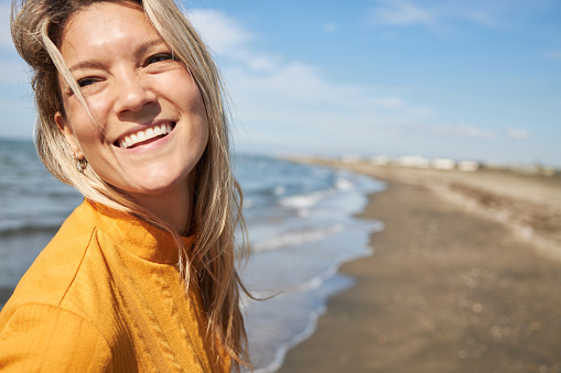 Happy woman enjoying day on a beach. It’s autumn and sun, perfect combination for vacation!