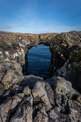A rock bridge above the blue waters of the sea. Iceland
