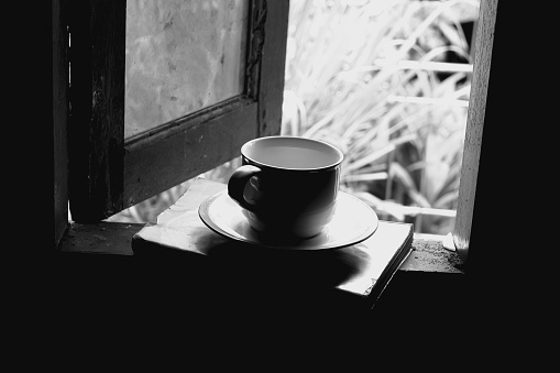 Cups and books are on the open window frame in the morning