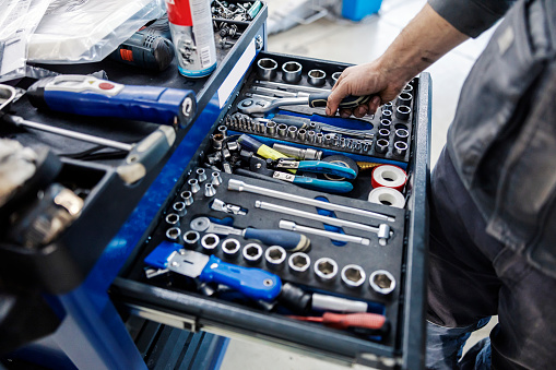 Close up of an auto-mechanic picking fools from toolbox at mechanic's workshop.