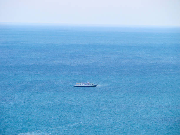 A ship in the middle of calm blue water and a clear sky on the horizon. Cruise yacht top view.