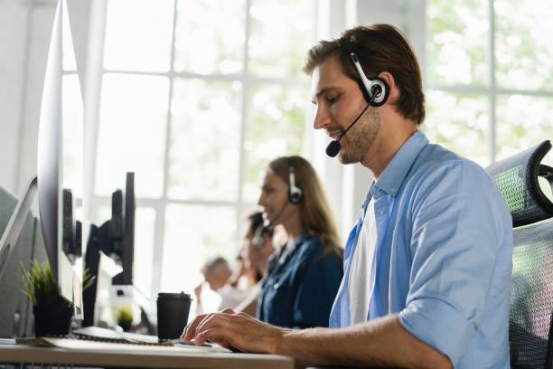 istock Beautiful business people in headsets are using computers and smiling while working in office 2045252530