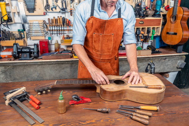 istock CRAFTSMAN LUTHIER IN HIS WORKSHOP REPAIRING A SPANISH CLASSICAL GUITAR. 2045255538