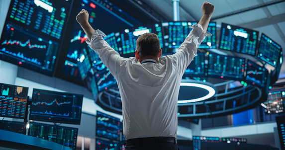 Close-up on a business man celebrating a successful investment on the stock market and watching growth graphs on a laptop