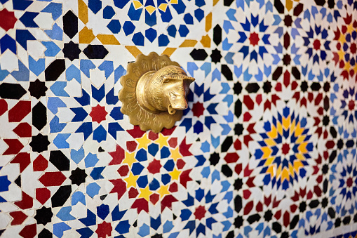 Close up of islamic mosaic pattern drinking fountain copper faucet in Chefchaouen, Morocco, North Africa.
