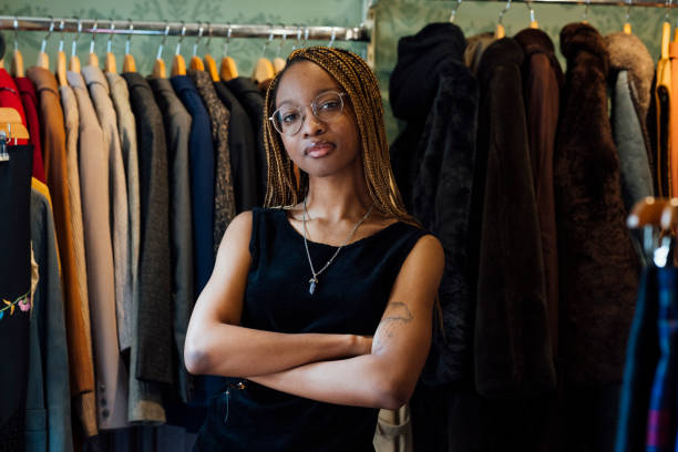 Woman working at a vintage clothing store. She is standing looking at the camera with her arms crossed. The store is in Durham, Northeast England.