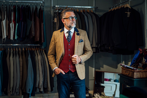 Man dressed formally in a waistcoat and suit jacket  standing inside of a vintage clothing store. He is looking away from the camera with a serious expression. The store is in Durham, Northeast England.