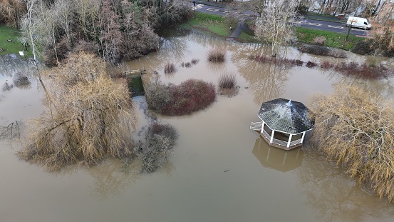 A gazebo surrounded by floodwaters, trees, bushes, and homes