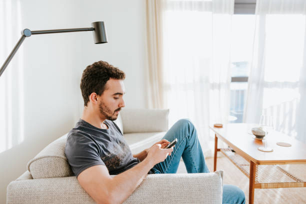 istock Relaxed on a sofa, a gay man uses his phone to order takeout 2045302366