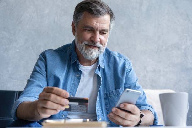 istock Smiling mature old man enjoying shopping in internet store using mobile phone applications 2045310804