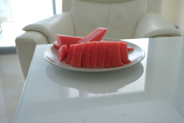 Colorful watermelon slices are neatly arranged in a bowl surrounded by fruit.