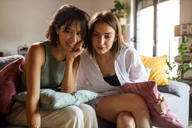 istock Two girlfriends sitting on the sofa, surfing the net via laptop 2045325227