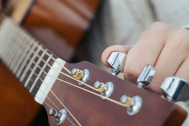 Female musician tuning guitar, close up shot