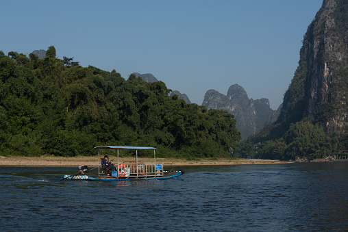Yangshuo County, Guilin City, Guangxi, China - October 16, 2023: A bamboo raft used to carry passengers to explore the scenery of the Li River sails across the Li River