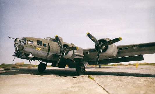 A scale model of the iconic B-17 Flying Fortress sitting on a scale model airfield. The B-17 was an American four-engined heavy bomber aircraft developed in the 1930s for the United States Army Air Corps and made by Boeing.