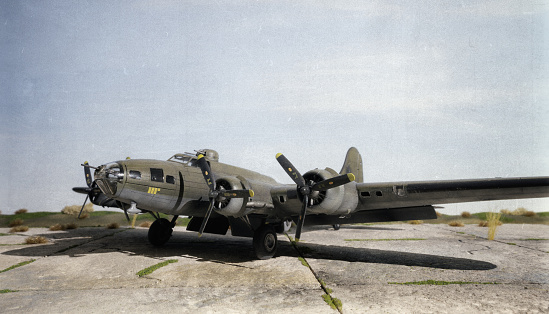 A scale model of the iconic B-17 Flying Fortress sitting on a scale model airfield. The B-17 was an American four-engined heavy bomber aircraft developed in the 1930s for the United States Army Air Corps and made by Boeing.