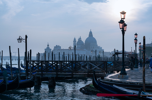Looking out across a line of gondolas on the magnificent Grand Canal in Venice at sunset, with the majestically-domed Santa Maria della Salute Basilica in the background.