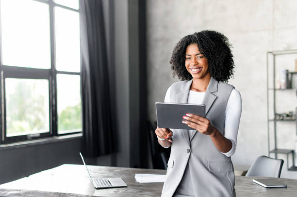 istock An ebullient African-American professional uses a digital tablet by a sunlit window 2045358722