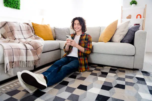 Full length photo of positive good mood guy dressed checkered shirt chatting modern gadget indoors house home room.